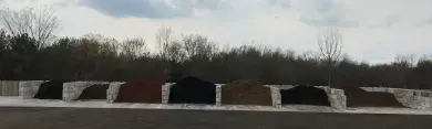 A row of various types and colors of mulch and soil stored in bins