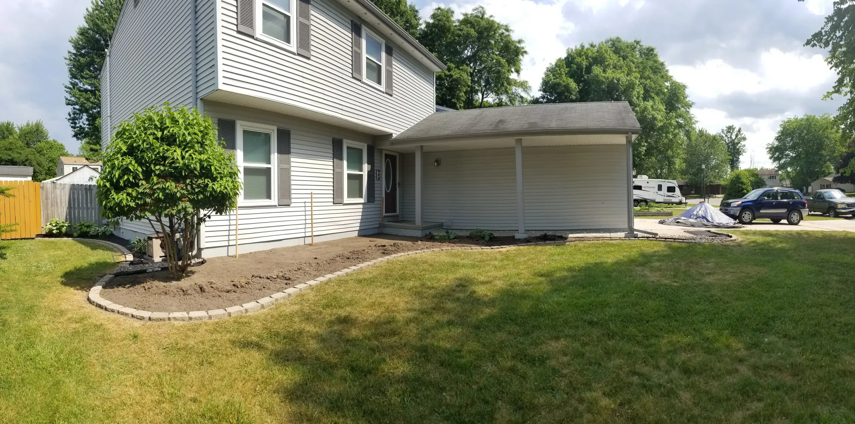 Fresh mulch layered around a well-tended home foundation bed in Milan, Michigan