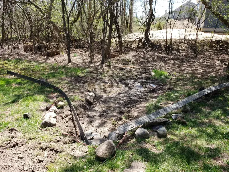 Landscape bed prepared with new edging and fieldstone under trees